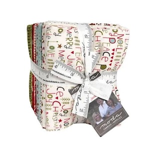 May include: A stack of Christmas-themed fabric squares tied with a white ribbon printed with measurements. The fabric features holiday words like "Merry", "Joy", and "Peace" in red and green on a cream background. A tag with the "Moda Fabrics & Supplies" logo is attached.