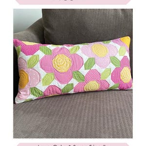 May include: A rectangular pillow with a floral design. The pillow features pink, yellow, and green flowers on a white background. The text "Flower Patch Pillow" is at the top. Finished size is 12" x 24".
