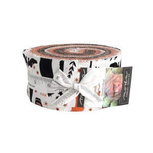 May include: A roll of fabric featuring a black and white print of bats, stars, and other Halloween-themed designs on a white background. The fabric is tied with a white ribbon and has a label that says "Sweetfire Road" and "moda fabrics - supplies".