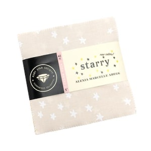 May include: A stack of beige fabric squares with white star patterns. A black and cream-colored label wraps around the fabric, displaying the text "starry" and "Ruby Star Society". The fabric squares are 5 inches in size.