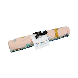 May include: A rolled up set of three pink, blue, and green fabric squares with a whimsical pattern of animals and objects. The fabric is labeled "whatnot RAGHDA COLEMAN VINHALE" and "The All Star Society".