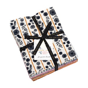 May include: A stack of 12 fat quarter bundles of fabric featuring a floral print in shades of blue, white, and yellow. The fabric is tied with a black ribbon and a tag that reads "Alexia Marcelli Aregg fat quarter bundle" and "Ruby Star Society".