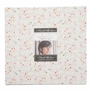 May include: A white fabric with a scattered pattern of colorful pins. The fabric has a Moda Fabrics label with the text "make time" and "by Aneela Hoey".