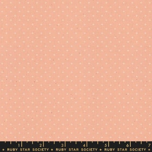 May include: A peach-colored fabric with a white plus sign pattern. The fabric has a subtle speckled texture. The fabric is marked with a ruler and the text "RUBY STAR SOCIETY".