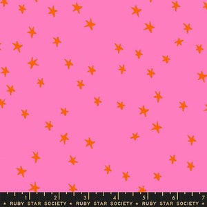 May include: Pink fabric with a repeating pattern of orange stars. The fabric is marked with a ruler in inches.