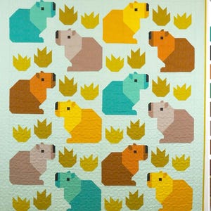 May include: A quilt featuring a repeating pattern of geometric capybaras in shades of teal, brown, yellow, and tan, interspersed with stylized yellow grass shapes. The background is a light blue-green.