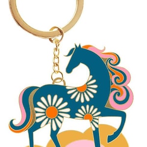 May include: A whimsical keychain featuring a blue horse with daisy patterns and a gold-colored ring. The horse has a pink and orange mane and tail, and is set against a backdrop of pink and yellow clouds.