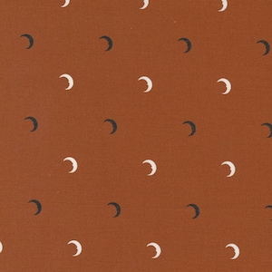 May include: A seamless pattern of white and black crescent moons on a brown background.