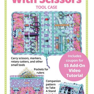 May include: A teal and pink tool case with the text "Running With Scissors". The case is open, displaying scissors, markers, and other tools. The image also shows a tote bag and a coupon for a video tutorial.