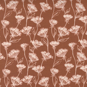 May include: A brown fabric with a white floral pattern. The pattern features delicate, stylized flowers with a repeating design.
