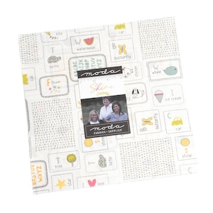 May include: A white fabric with a repeating pattern of colorful squares. Each square features a letter of the alphabet, a simple illustration, and the word for the illustration. The fabric is labeled "Shine" and "Moda Fabrics - Supplies".
