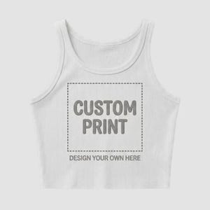 May include: White ribbed crop top with the text "CUSTOM PRINT" inside a dotted square, with the words "DESIGN YOUR OWN HERE" below. The top has a scoop neck and is sleeveless.