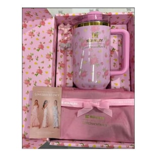 Pode incluir: Uma caneca Stanley Loveshackfancy rosa com al&ccedil;a, tampa e padr&atilde;o floral, apresentada numa caixa de presente a condizer. A caixa inclui uma colher de mexer rosa, uma bolsa rosa e um cart&atilde;o com o log&oacute;tipo Loveshackfancy.
