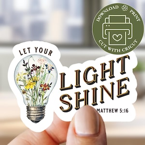 May include: A sticker with the words "LET YOUR LIGHT SHINE" and "LIGHT SHINE" in a vintage font. The "LIGHT SHINE" text is in gold and black. The sticker also features a lightbulb filled with flowers and the text "MATTHEW 5:16".