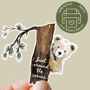 May include: A watercolor sticker featuring a light brown bear peeking from behind a tree trunk. The tree trunk has the text "Just around the corner." A green circle with a printer icon and the words "Download Print Cut with Cricut" is also included.