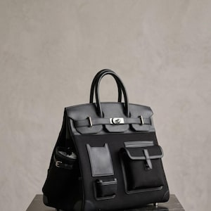 Bolso utilitario estructurado de lona, maletín de trabajo con múltiples bolsillos y ribete de cuero negro.