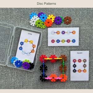 May include: A collection of colorful disc-shaped building blocks and pattern cards. The blocks are in various colors, including blue, green, orange, and purple. The cards show circle and square patterns. The text "Disc Patterns" is at the top.
