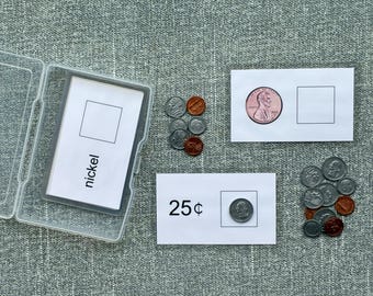 May include: A coin matching game with a clear plastic case containing cards labeled "nickel". Two white cards show a penny and a quarter with a blank square. Loose coins are scattered around the cards. The text "Digital Download - Coin Matching" is at the top.