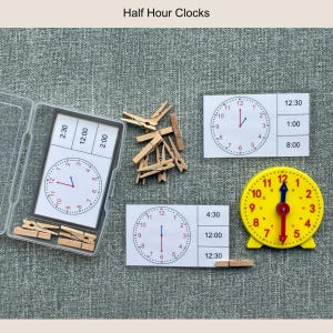 May include: Educational clock set with the text "Half Hour Clocks". The set includes a yellow clock, clock cards, and wooden clothespins. The clocks display different times, such as 12:30, 1:00, and 8:00. The set is designed for learning about time.