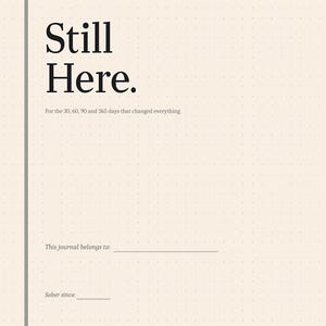 Op de afbeelding: Een beige notitieboek met een gestippeld rasterpatroon. De omslag bevat de tekst "Still Here." en "For the 30, 60, 90 and 365 days that changed everything." Bevat de prompts: "This journal belongs to:" en "Sober since:"