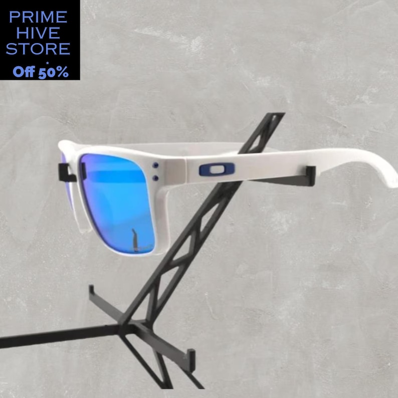 Peut inclure: Des lunettes de soleil blanches avec des verres bleus sont pr&eacute;sent&eacute;es sur un pr&eacute;sentoir noir. Les lunettes ont une monture blanche avec un logo bleu sur le c&ocirc;t&eacute;. Les verres refl&egrave;tent une couleur bleu vif. Le texte "PRIME HIVE STORE" et "Off 50%" est en haut &agrave; gauche.