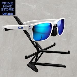 Peut inclure: Des lunettes de soleil blanches avec des verres bleus miroir sont pr&eacute;sent&eacute;es sur un pr&eacute;sentoir en m&eacute;tal noir. Les lunettes ont une monture blanche avec des accents bleus. Le pr&eacute;sentoir a un design g&eacute;om&eacute;trique. Le texte "PRIME HIVE STORE" et "Off 50%" est dans le coin sup&eacute;rieur gauche.