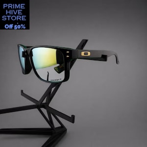 Peut inclure: Lunettes de soleil noires avec verres miroit&eacute;s, pr&eacute;sent&eacute;es sur un pr&eacute;sentoir noir. Les lunettes ont une monture rectangulaire avec un logo dor&eacute; sur la branche. Le texte "PRIZM P" est visible sur le verre. Le texte "PRIME HIVE STORE Off 50%" est &eacute;galement visible.