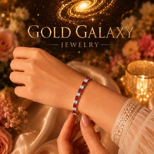 Può includere: Viene mostrato un braccialetto d'oro con pietre quadrate rosse e bianche alternate. Il braccialetto è su un polso, con la scritta "GOLD GALAXY JEWELRY" in lettere dorate sopra. Lo sfondo presenta un design galattico ed elementi floreali.