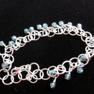 May include: A silver chain bracelet with dangling blue crystal beads.
