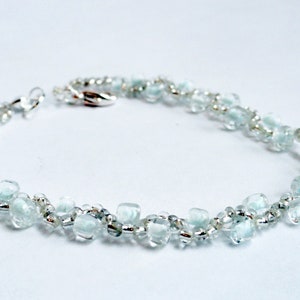May include: A delicate bracelet made with light blue and silver beads. The bracelet is made with small, faceted beads that create a shimmering effect.