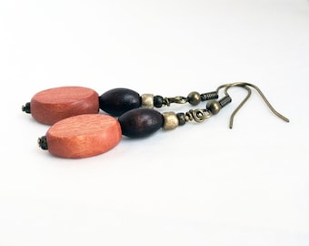 May include: A pair of wooden earrings with a brown and red color scheme. The earrings are made of oval-shaped wooden beads and have a bronze hook.