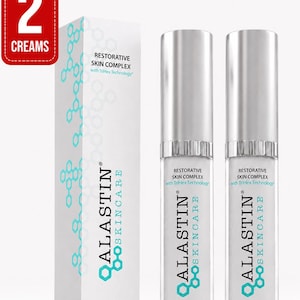 May include: A pack of two Alastin Skincare Restorative Skin Complex creams, each in a 1.0 fl. oz. bottle with a silver cap, alongside a tall white rectangular box featuring a teal hexagonal pattern and the text Restorative Skin Complex.