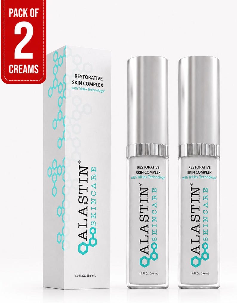 May include: A pack of two Alastin Skincare Restorative Skin Complex creams, each in a 1.0 fl. oz. bottle with a silver cap, alongside a tall white rectangular box featuring a teal hexagonal pattern and the text Restorative Skin Complex.