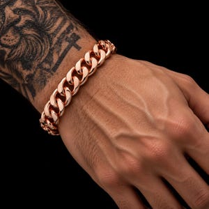 Op de afbeelding: Een gepolijste roségoudkleurige gourmetarmband met dikke, in elkaar grijpende ovale schakels. De armband heeft een hoogglanzende metalen afwerking en een veilig sluitingsmechanisme, met een klassiek ontwerp van zware schakels.