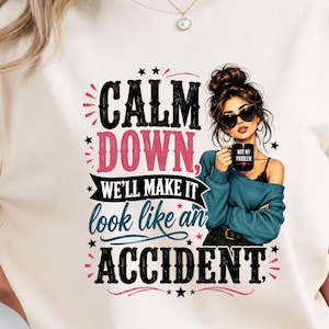 May include: A cream-colored t-shirt featuring a graphic illustration of a person with a messy bun and sunglasses holding a black mug that says NOT MY PROBLEM. The text reads CALM DOWN, WE'LL MAKE IT look like an ACCIDENT, accented with stars.