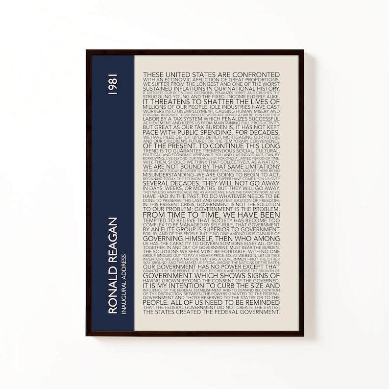 K&ouml;nnte beinhalten: Gerahmter Druck mit Text aus Ronald Reagans Antrittsrede von 1981. Das Kunstwerk hat einen cremefarbenen Hintergrund mit schwarzem Text. Ein vertikaler marineblauer Streifen auf der linken Seite enth&auml;lt den Text "Ronald Reagan" und "1981".