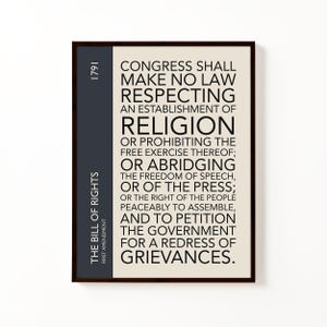 May include: Framed print featuring the text of the First Amendment to the United States Constitution. The text is in black on an off-white background, with a dark blue sidebar that reads "The Bill of Rights, First Amendment, 1791."