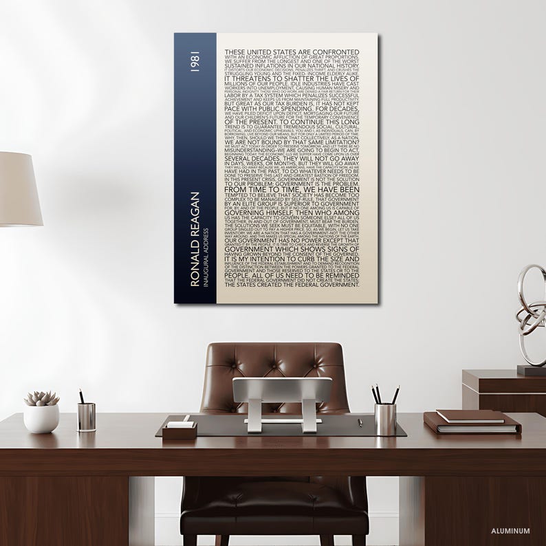 K&ouml;nnte beinhalten: Ein Wandkunstwerk aus Aluminium mit einem Teil der Antrittsrede von Ronald Reagan von 1981. Der Text wird vertikal mit einem blau-wei&szlig;en Farbverlauf angezeigt. Das Kunstwerk wird in einer B&uuml;roumgebung ausgestellt.