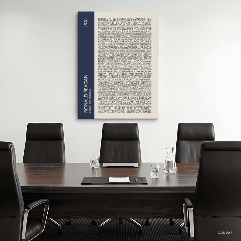 K&ouml;nnte beinhalten: Leinwanddruck mit Text aus Ronald Reagans Antrittsrede von 1981. Das Kunstwerk hat einen cremefarbenen Hintergrund mit schwarzem Text. Ein vertikaler marineblauer Streifen auf der linken Seite zeigt das Jahr und den Namen des Pr&auml;sidenten.