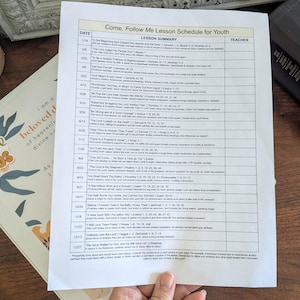 以下が含まれることがあります： 「Come, Follow Me Lesson Schedule for Youth」というタイトルの印刷されたレッスン スケジュールが木製の表面にあります。スケジュールは白地に黒文字で、日付、レッスンの概要、教師の列が記載されています。「choose JESUS」という言葉が入った本とノートも表示されています。