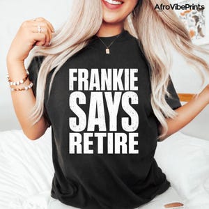 May include: Black t-shirt with the text "FRANKIE SAYS RETIRE" in large, white, bold letters. The shirt is a casual style, suitable for everyday wear. The design is centered on the front of the shirt.