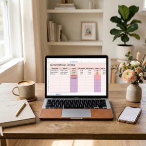 May include: A silver laptop with a brown leather skin on the palm rest displaying a spreadsheet titled CLIENT PIPELINE Q2 2024. The screen shows columns for client name, project, status, last contact, next follow-up, priority, and estimated value.