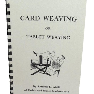 May include: A spiral-bound instructional book titled CARD WEAVING OR TABLET WEAVING by Russell E. Groff of Robin and Russ Handweavers. The cover is light gray with black text and a black line drawing of a person operating a weaving loom.
