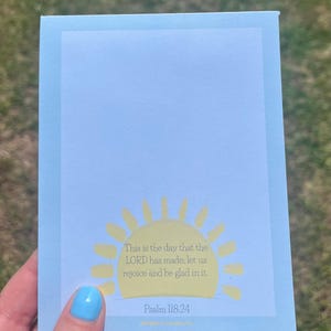 May include: A light blue notepad with a light blue border. The notepad features a yellow sun graphic and the text "This is the day that the LORD has made; let us rejoice and be glad in it. Psalm 118:24."