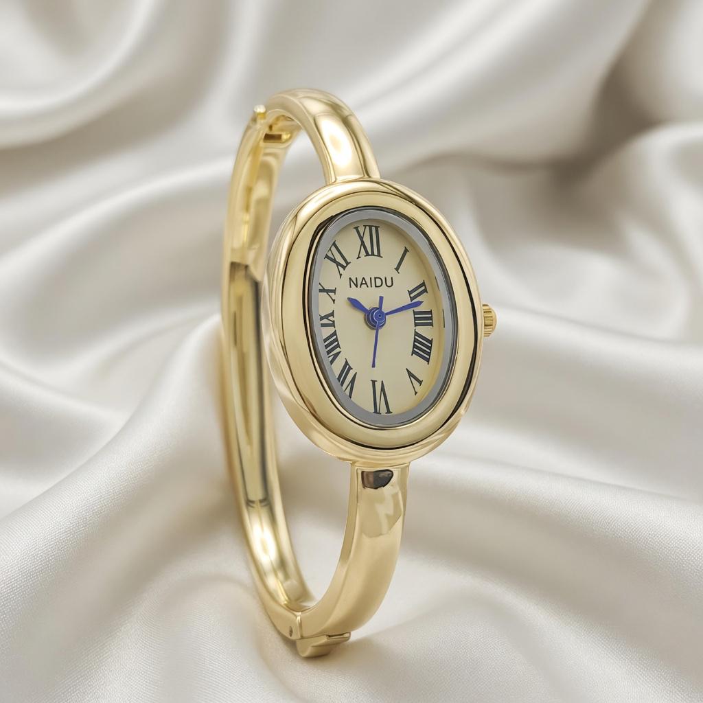 Damen Quarz Armbanduhr mit ovalem Gold Gehäuse, Gold Ziffernblatt und Armreif.