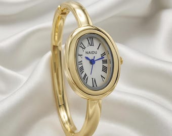 Women's quartz wristwatch with oval gold case, white dial and bangle band.