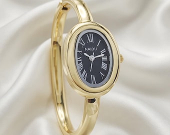 Women's quartz wristwatch with oval gold case, black dial and bangle band.