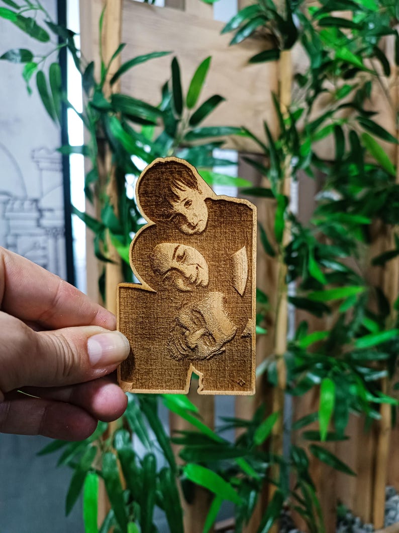 May include: A wooden plaque featuring a carved image of two people embracing. The plaque is rectangular with a unique cutout design. The wood has a warm, natural tone, and the carving details are visible. The background includes bamboo stalks and green leaves.