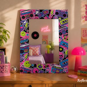 May include: A rectangular wall mirror featuring a vibrant border decorated with colorful 1980s-inspired graphics, including boomboxes, cassette tapes, musical notes, lightning bolts, and smiley faces in shades of neon pink, blue, and purple.