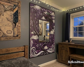 May include: A large, rectangular mirror with a black frame and a purple and white illustration. The artwork depicts a figure in a hat, clouds, and floral elements. The mirror is mounted on a gray wall in a bedroom setting.